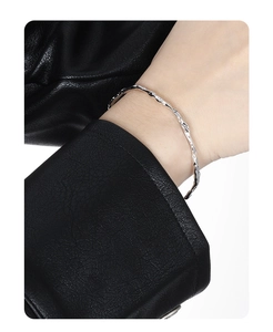 Detailed view of silver lava texture minimalist bangle worn over a black leather sleeve