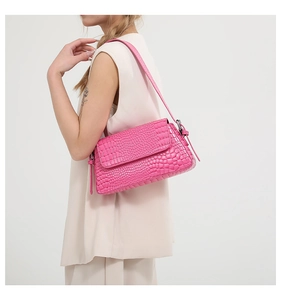 Pink faux crocodile leather shoulder bag styled on a model wearing a beige outfit