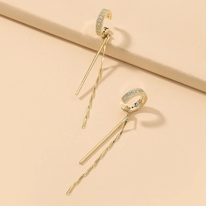 Macro shot of gold plated C-shaped ear cuffs featuring long tassel and sparkling zircon
