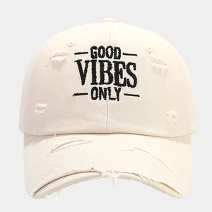 Detail of Good Vibes Only embroidery and distressed ripped texture on beige baseball cap