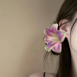 Elegant purple and green gradient lily flower hair clip worn by a model in natural light