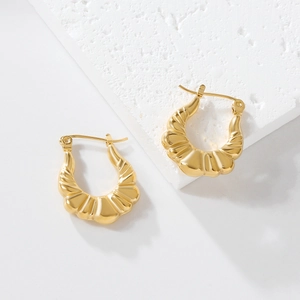 Detail shot of golden hoop earrings featuring a unique cocoon-like pleated texture finish