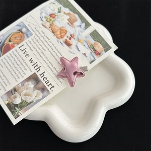 Close-up of pink star-shaped hair clip on white petal plate with elegant aesthetic