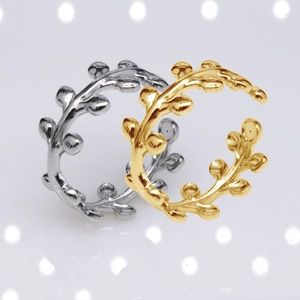 Detail view of gold and silver leaf pattern stainless steel open rings with bokeh effect