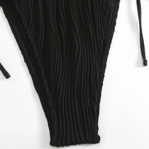 Dettaglio macro del tessuto a coste nere e dei laccetti laterali dello slip bikini