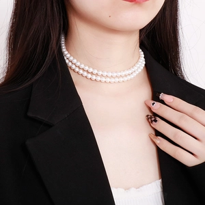 Close-up of double-layer pearl choker necklace on model wearing black blazer