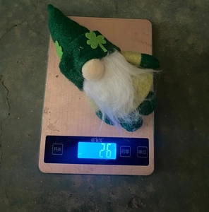 Close-up of lightweight St. Patrick's Day gnome being weighed at 26g on digital scale