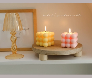 Detailed view of pink and yellow Rubik's cube bubble candles on a wooden tray