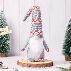 Close-up of Christmas gnome with snowflake hat on wooden stump with festive pine cones