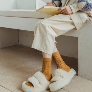 Chaussettes moutarde en maille torsadée assorties à des pantoufles pelucheuses blanc cassé