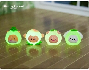 Close-up of luminous resin animal figurines glowing on a wooden surface in the dark