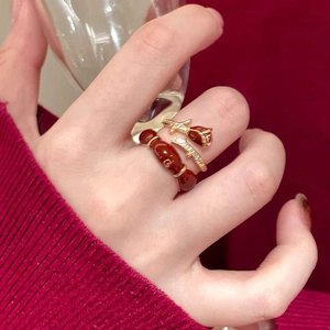 Detail of 14K gold plated rose flower ring and dark red beaded ring set on hand