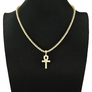 Gold tennis chain with Ankh cross pendant featuring small white gemstones on a black bust