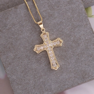 Close-up of 18K gold plated cross pendant with micro-pave cubic zirconia on grey stone
