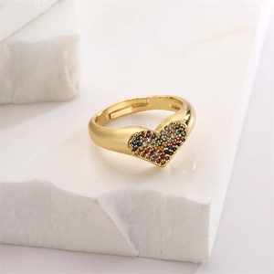 Detail of gold heart ring with colorful zircon stones on a white stone pedestal