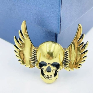 Punk style gold-plated winged skull brooch for Halloween with black detailing