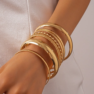 Close-up of set of gold geometric metal bangles with high gloss finish on model wrist