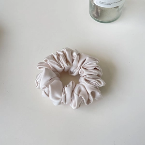 Elegant champagne satin scrunchie with soft silk texture and ruffled pleat design