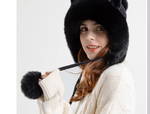 Detail of black winter knit hat with cat ears and large plush pompoms on white background