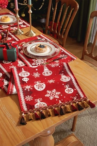 Close-up of red Christmas table runner with white snowflakes and festive tassels on wood