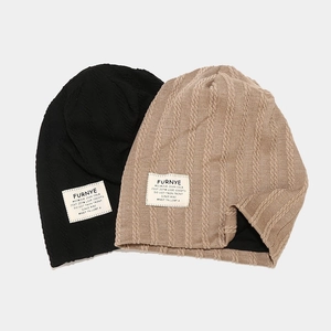 Cable knit beanie hats in black and khaki with brand labels for autumn and winter