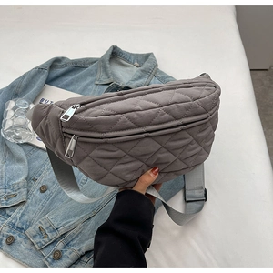 Detail of grey quilted crossbody chest bag with adjustable strap and metallic zipper closure