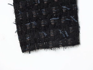 Close-up of black and navy tweed fabric with silver metallic threads and frayed edges