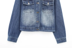 Detail of washed denim jacket featuring metal buttons and high-quality stitching