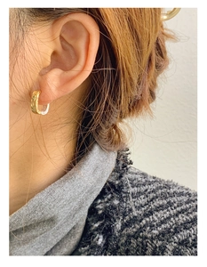 Close-up of a model wearing a two-tone silver and gold lava textured earring