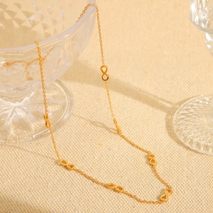 Detail of 18K gold-plated infinity link necklace on a rustic beige linen background