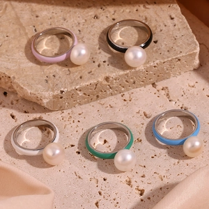 Detailed macro of colorful enamel rings with white pearls on a textured stone surface