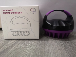 Detail of purple silicone shampoo brush with non-slip handle and its retail packaging