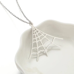 Macro shot of silver spider web pendant on a white ceramic plate with fine link chain