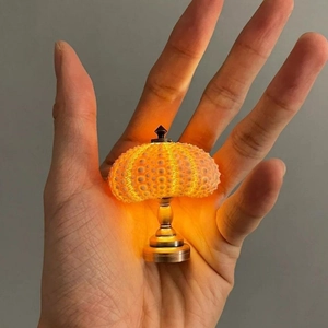 Close-up of a mini sea urchin night light with warm yellow glow held in hand