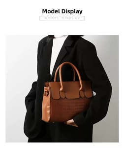 Detail of brown tote bag featuring crocodile embossed texture and metal D-ring accents