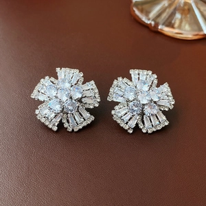 Macro shot of silver flower earrings with white zircon stones on brown leather background