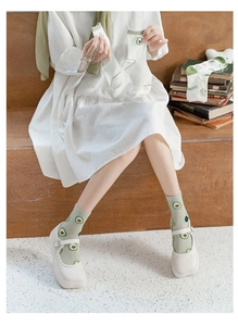 Close-up of light green mid-calf cotton socks with cute cartoon avocado prints for women