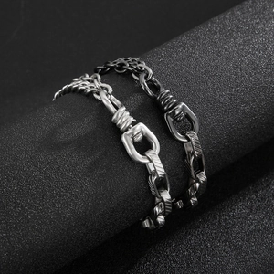 Chunky stainless steel chain link bracelets in silver and black on a dark display
