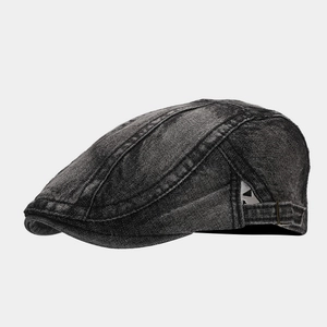 Detail view of washed denim flat cap showing metal adjustment buckle and contrast stitching