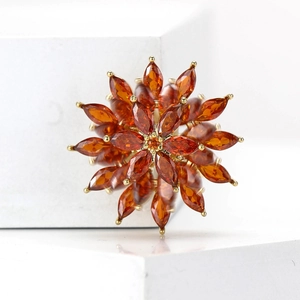 Detail of elegant gold snowflake brooch with marquise-cut orange-brown zircon stones