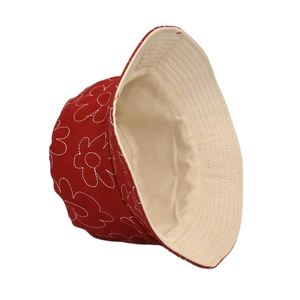 Détail d'un chapeau bob en coton rouge foncé avec broderie florale et doublure beige