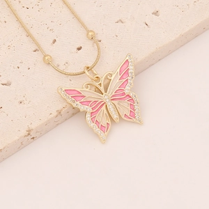 Detail of gold butterfly necklace with pink enamel and sparkling crystals on stone base