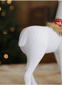 Detailed view of white flocked Christmas reindeer with red scarf and soft bokeh lighting