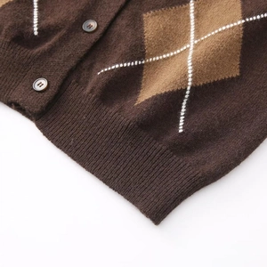 Detailansicht der Strickjacke mit Argyle-Muster, braunen Harzknöpfen und Rippbündchen