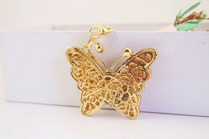 Detailed close-up of golden metal butterfly keychain with intricate hollowed patterns