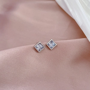 Detailed close-up of square cut lavender zircon earrings on soft pink silk fabric