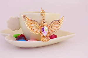Macro detail of eagle keychain with golden finish and iridescent teardrop gemstone