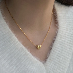 Detailed close-up of a delicate golden S925 sterling silver heart necklace on neck