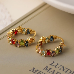 Chic gold-plated hoop earrings with vibrant multi-colored zircon stones on a book
