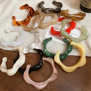 Irregular wave acrylic open cuff bracelets in multiple colors on rustic linen and wood